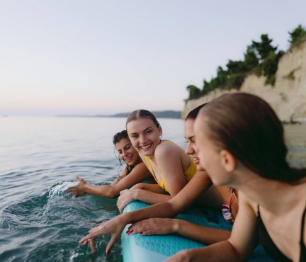 Vier vriendinnen op een surfplank in het water.